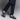 A person in dark blue jeans and white socks stands against a neutral background wearing Anthony Veers Beaumont Double Monk Loafer in Smoke Slate Grey Suede, highlighting the fashion-forward footwear crafted with Bologna construction.
