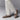 A person wearing Beaumont Double Monk Loafers by Anthony Veer, made from Terra Dusk Brown suede, pairs them with white socks and cream pants. Theyre on a gray surface with one foot playfully in front of the other.